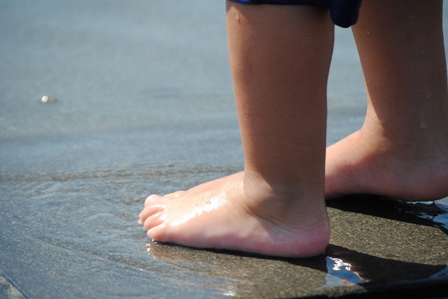 Criança com pés na água do mar