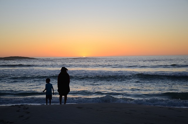 Mãe e filho vendo o pôr do sol na Praia